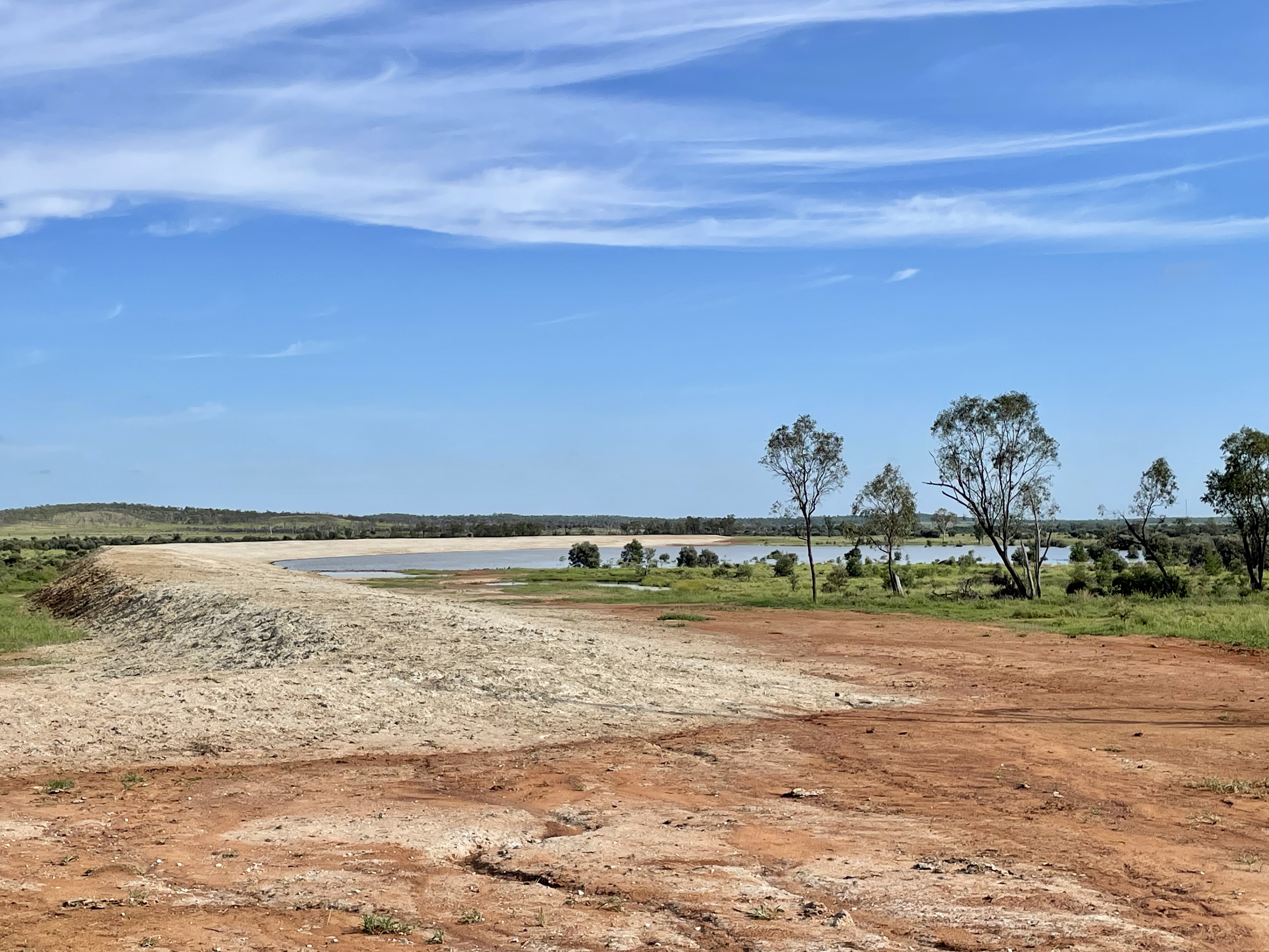 Dam bank construction showing earthworks with water in background, Central Queensland